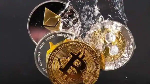 Souvenir tokens representing cryptocurrency networks Bitcoin, Ethereum, Dogecoin and Ripple plunge into water in this illustration. (REUTERS)