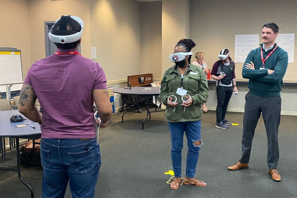 Austin Doctor watches as two people use virtual reality headsets.