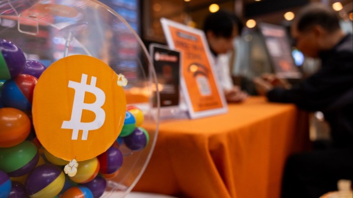 A bitcoin logo is displayed on a gift dispenser containing colourful capsules at the Bithumb exchange office in Seoul, South Korea