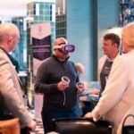 Learner with VR headset with three adults stood around watching them