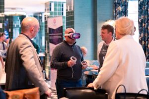 Learner with VR headset with three adults stood around watching them